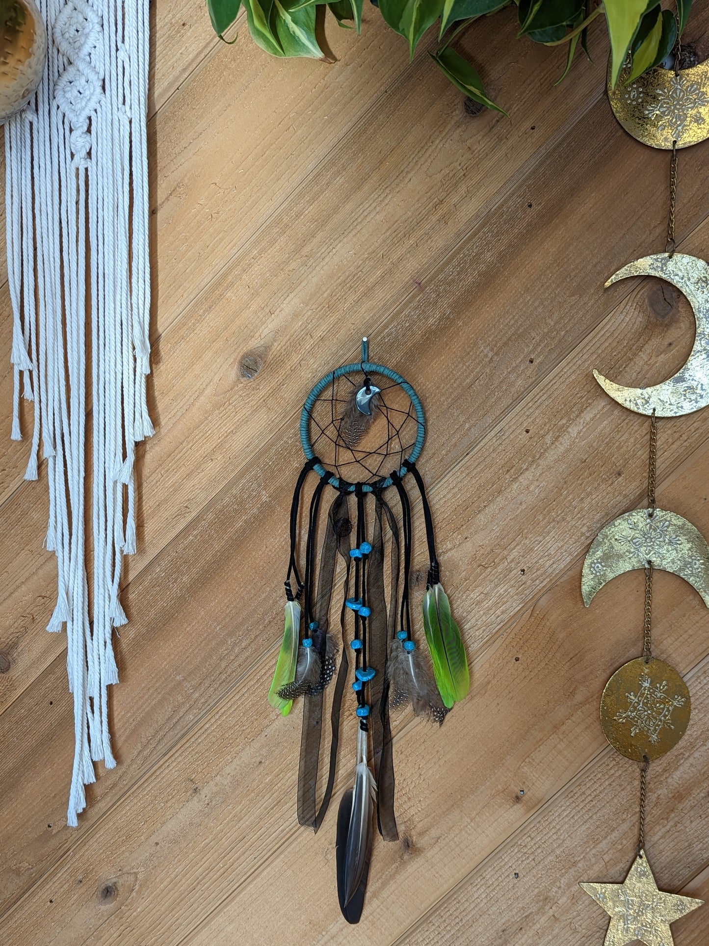 A wall-mounted dream catcher adorned with feathers and a crescent moon, capturing the essence of dreams and spirituality.