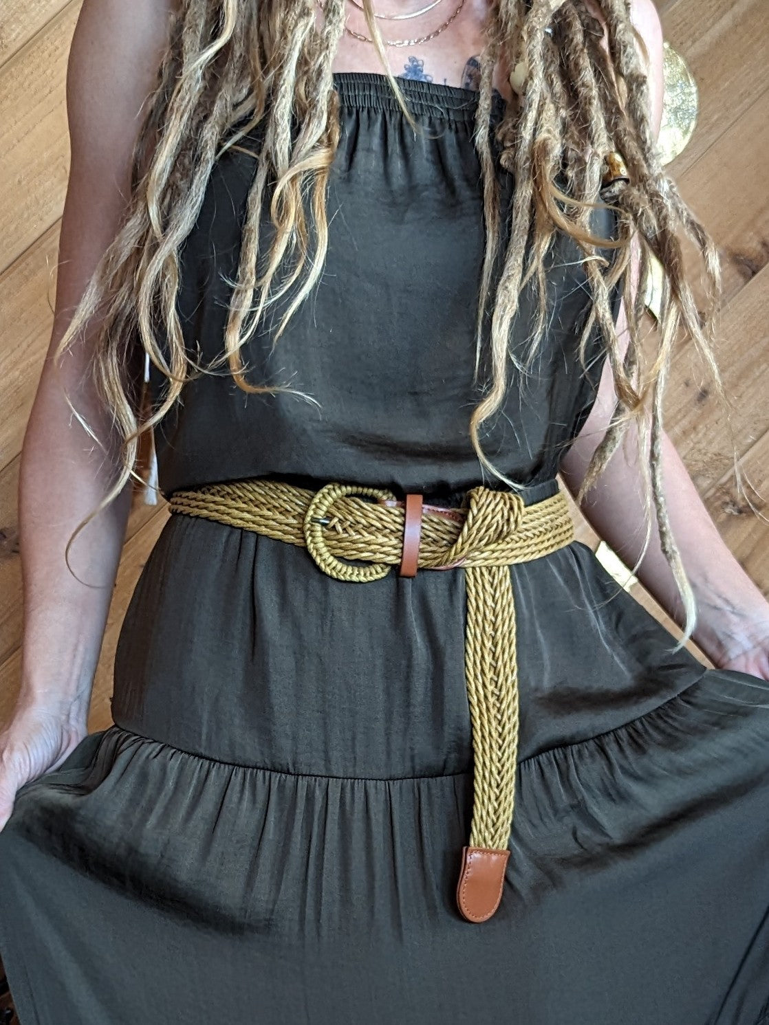 Woman with dreadlocks in a dress and yellow belt.