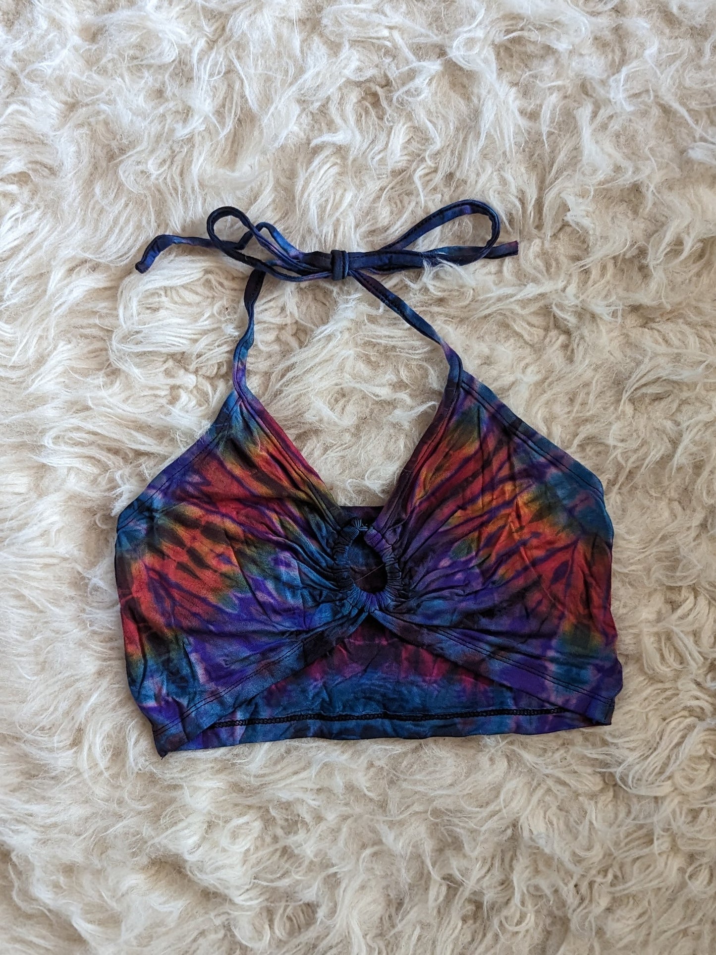 Purple tie dye halter top lays on white fur.